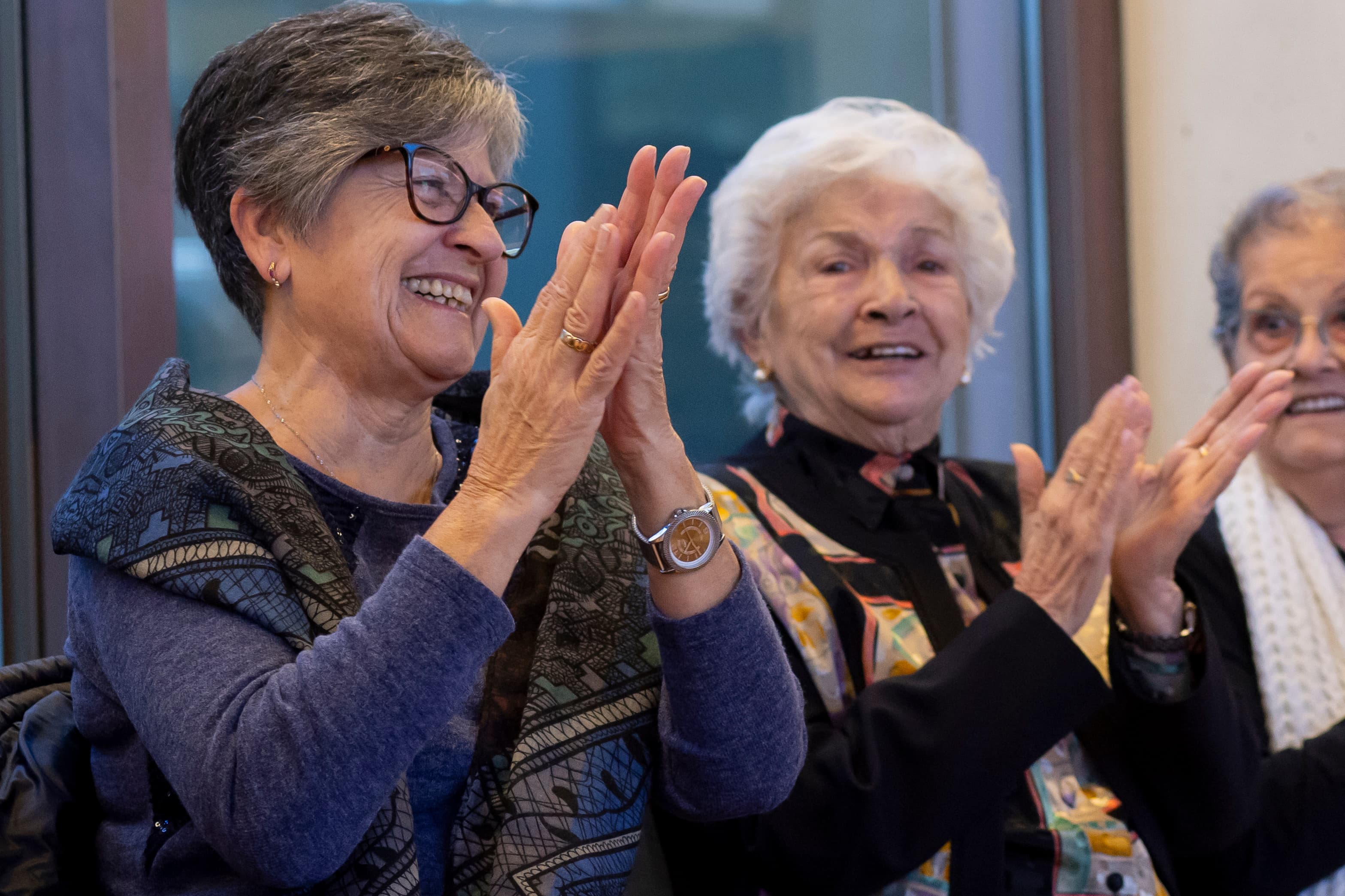 Dues dones aplaudint en un acte cultural.